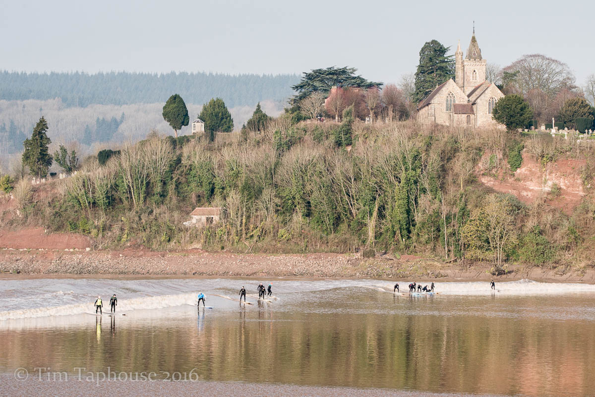 Many surfers as the bore passes below Newnham on Severn Church