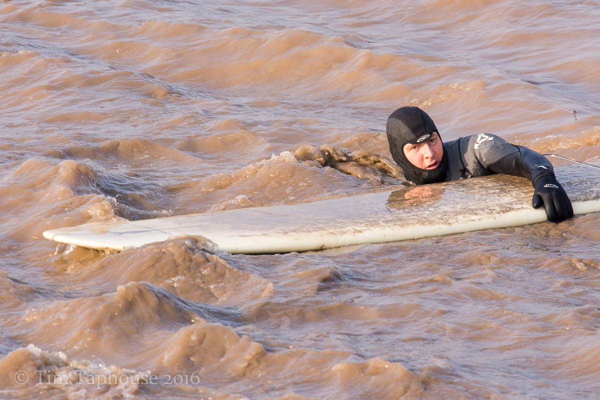 Fast flowing muddy water as surfers get out of the river Severn